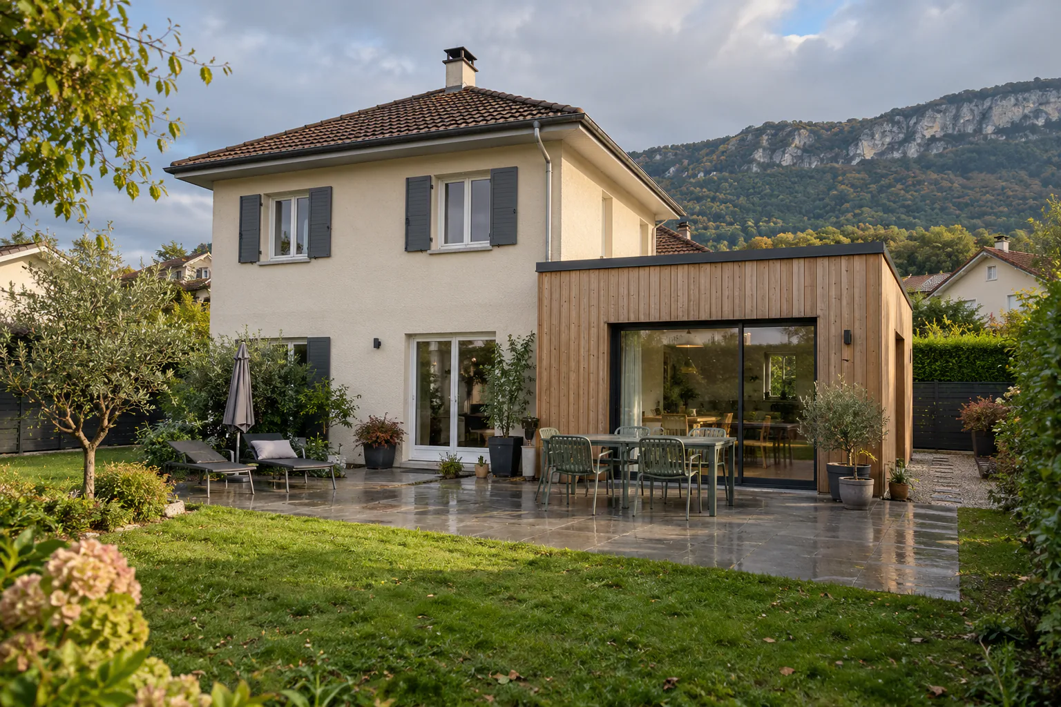Pavillon et extension bois devant la pelouse Une extension latérale en bois à large baie vitrée prolonge un pavillon à toiture à quatre pans.