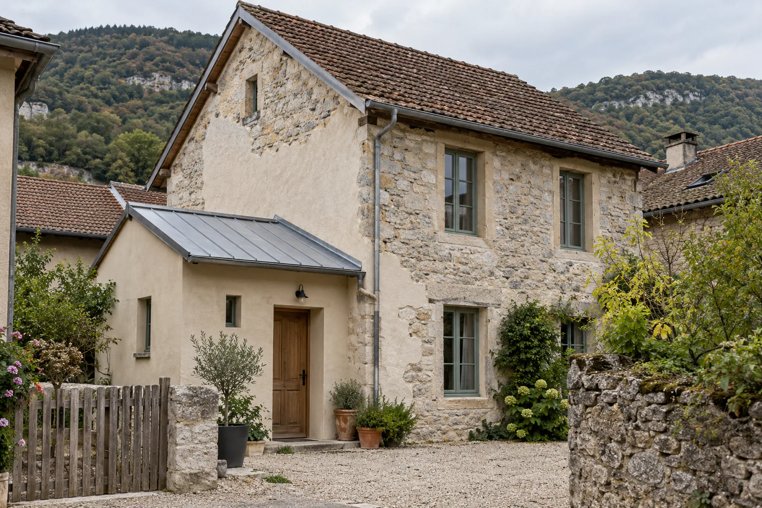 Entrée neuve devant une maison en pierre Un petit volume clair à toit métallique abrite l’entrée d’une maison ancienne en pierre, au fond d’une cour.