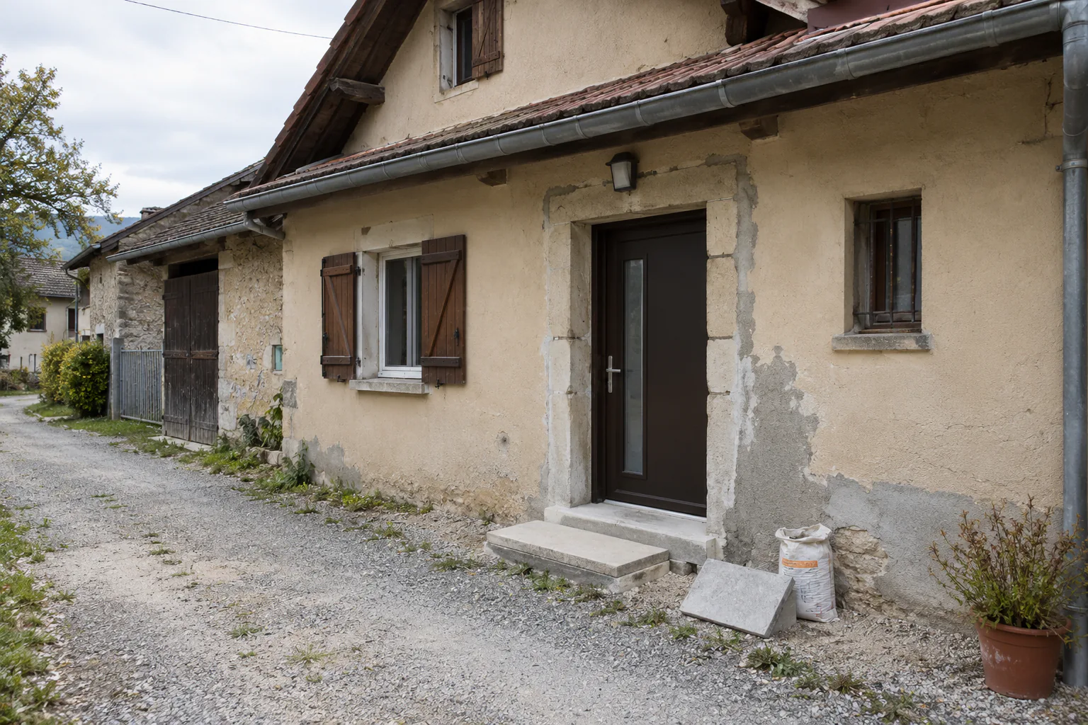 Entrée de maison et enduit ancien décapé Autour d’une porte sombre, l’enduit d’une façade ancienne est piqué et laisse apparaître la maçonnerie.