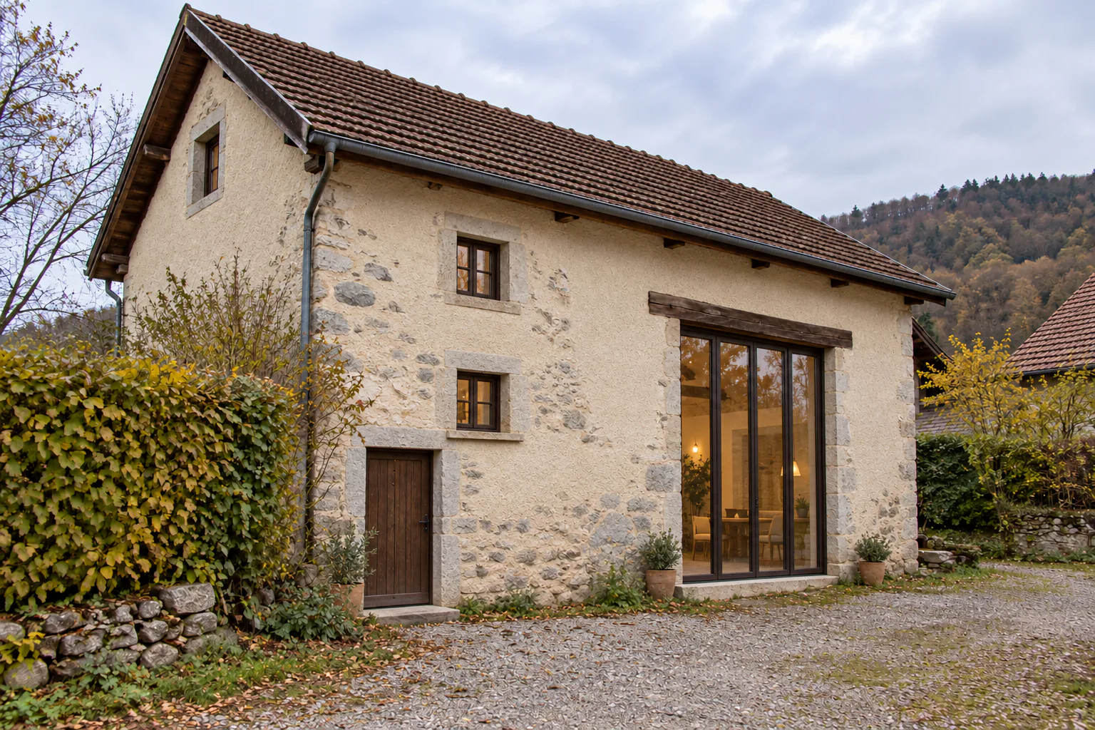 Grange en pierre avec baie vitrée Petit bâtiment en pierre et enduit clair, avec grande baie vitrée sous une toiture en tuiles.