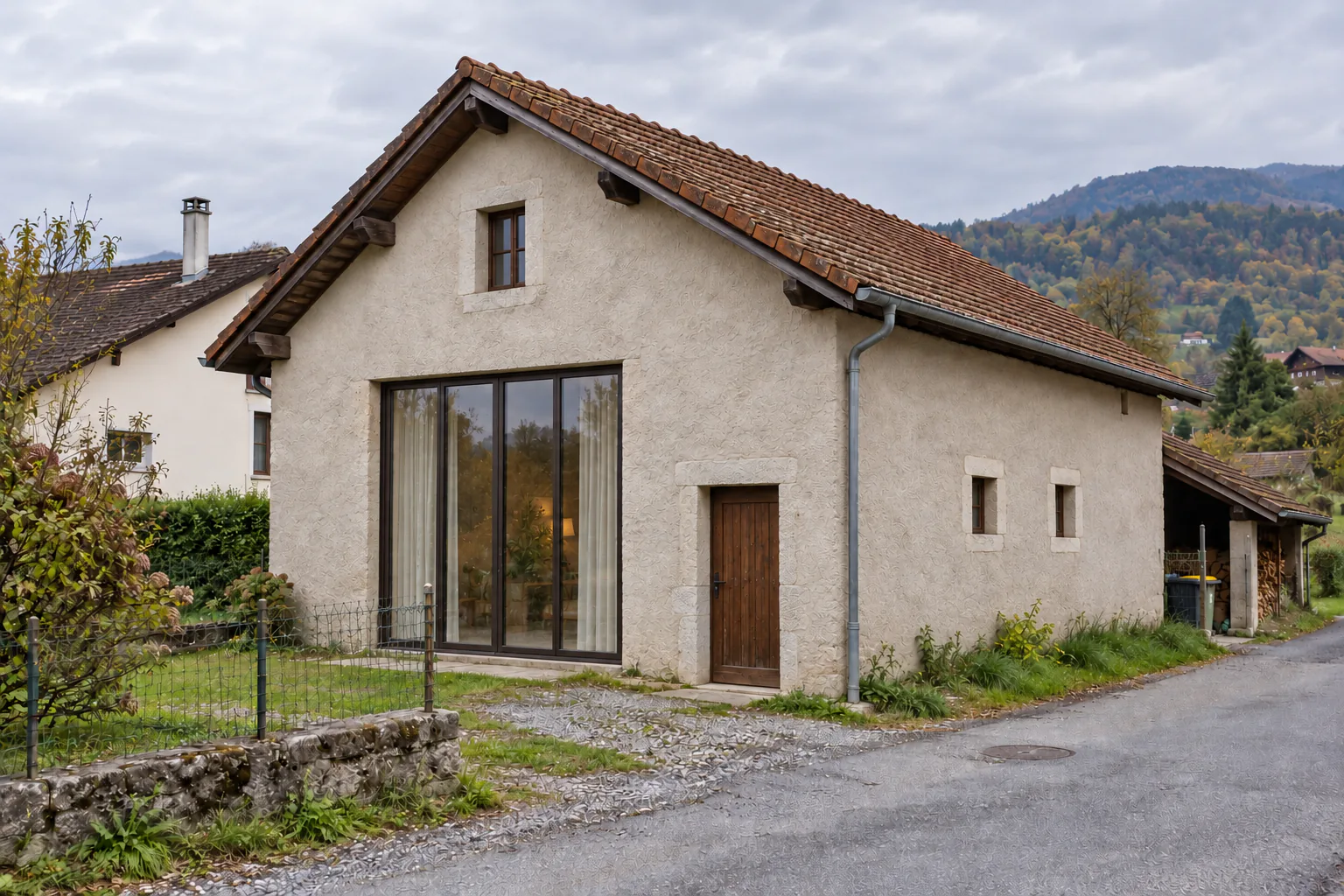 Grange claire avec grande baie de pignon Bâtiment à toiture en tuiles avec grande baie vitrée de pignon et petit appentis latéral.