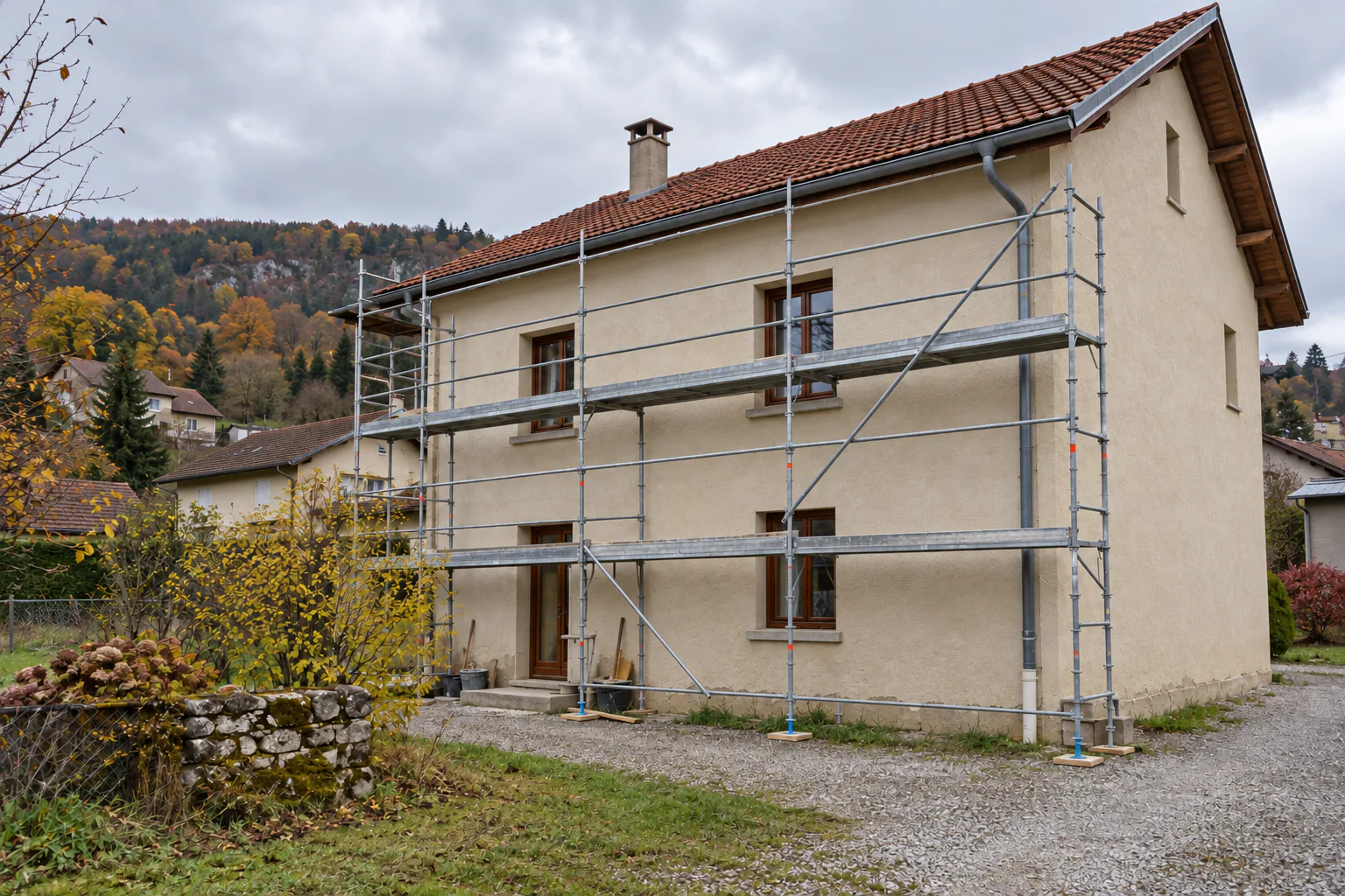 Maison à étage et toiture en tuiles avec échafaudage devant sa façade.
