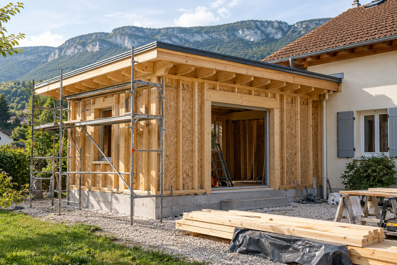 Ossature bois ouverte devant une maison Montants et poutres d'une extension bois avec échafaudage et maison en arrière-plan.