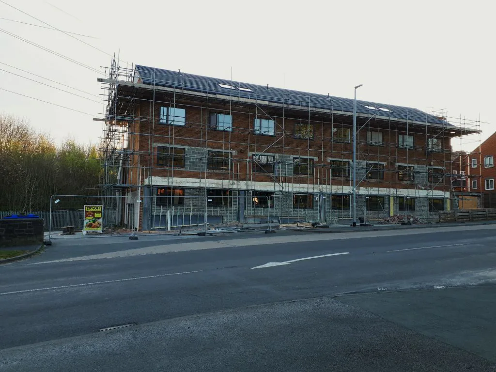 Immeuble en brique sous échafaudage Long immeuble en brique avec échafaudage sur plusieurs niveaux au bord d'une route.