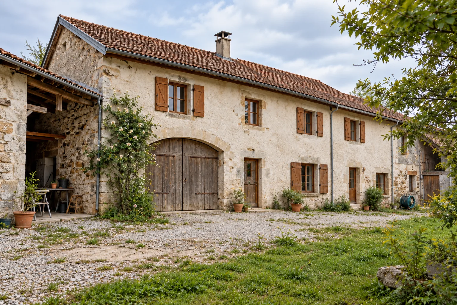 Avant : La même longue ferme avec sa grande ouverture cintrée fermée par une porte de grange en bois.